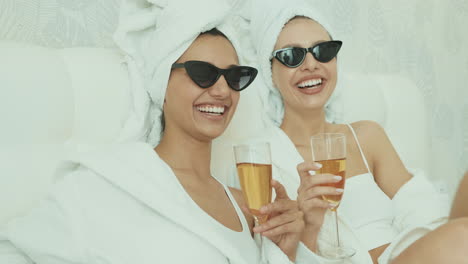 two women relaxing with champagne in bathrobes