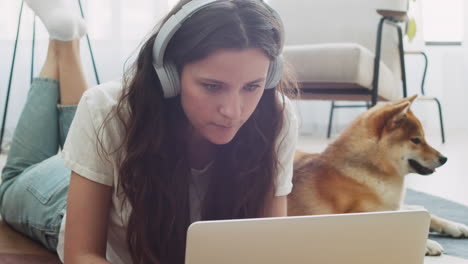 mujer joven que trabaja en su computadora portátil en casa junto a su perro 6