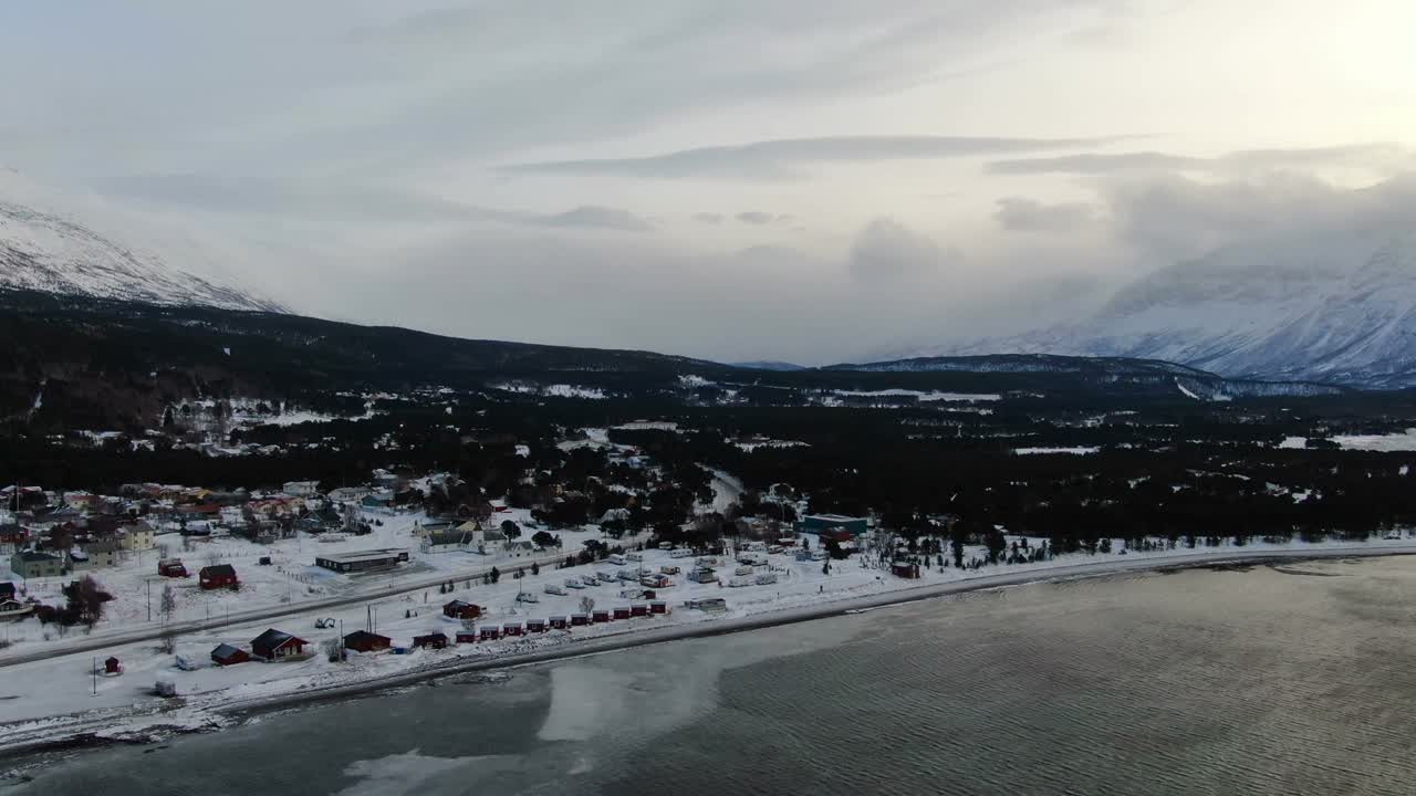 volando sobre un pequeño pueblo y lyngenfjord en los alpes de lyngen, noruega, ártico