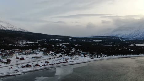 volando sobre un pequeño pueblo y lyngenfjord en los alpes de lyngen, noruega, ártico