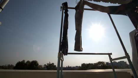 as the sun shines on an urban apartment balcony, laundry is hung up to dry and blocks the sunrays