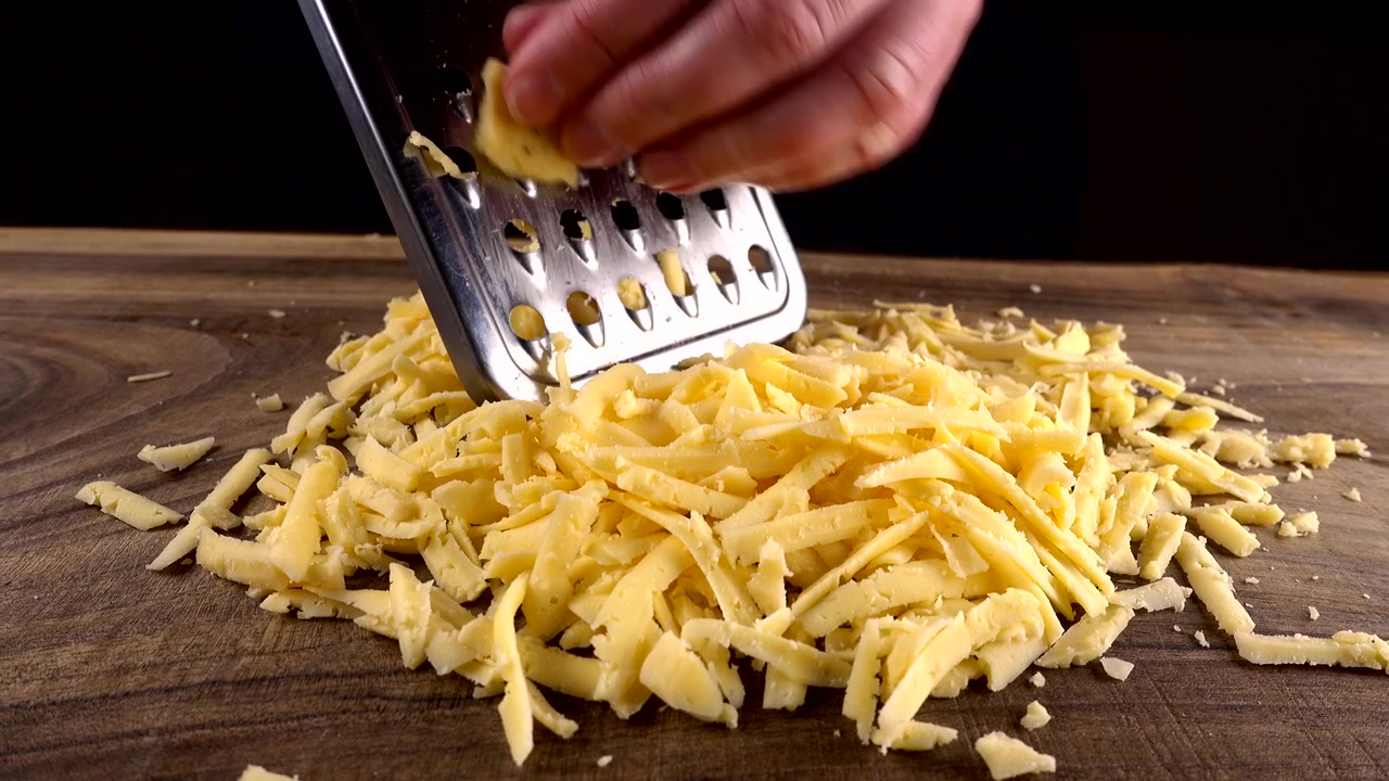 Lo chef strofina formaggio grattugiato su un tagliere