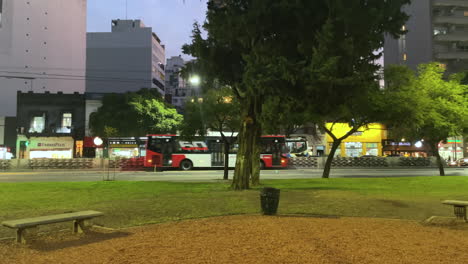 view from the park to the roadway, a woman with a stroller is walking along the street