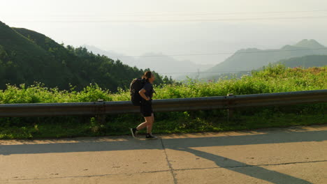 confident young woman wearing a heavy backpack walks powerfully uphill while hiking a mountainous