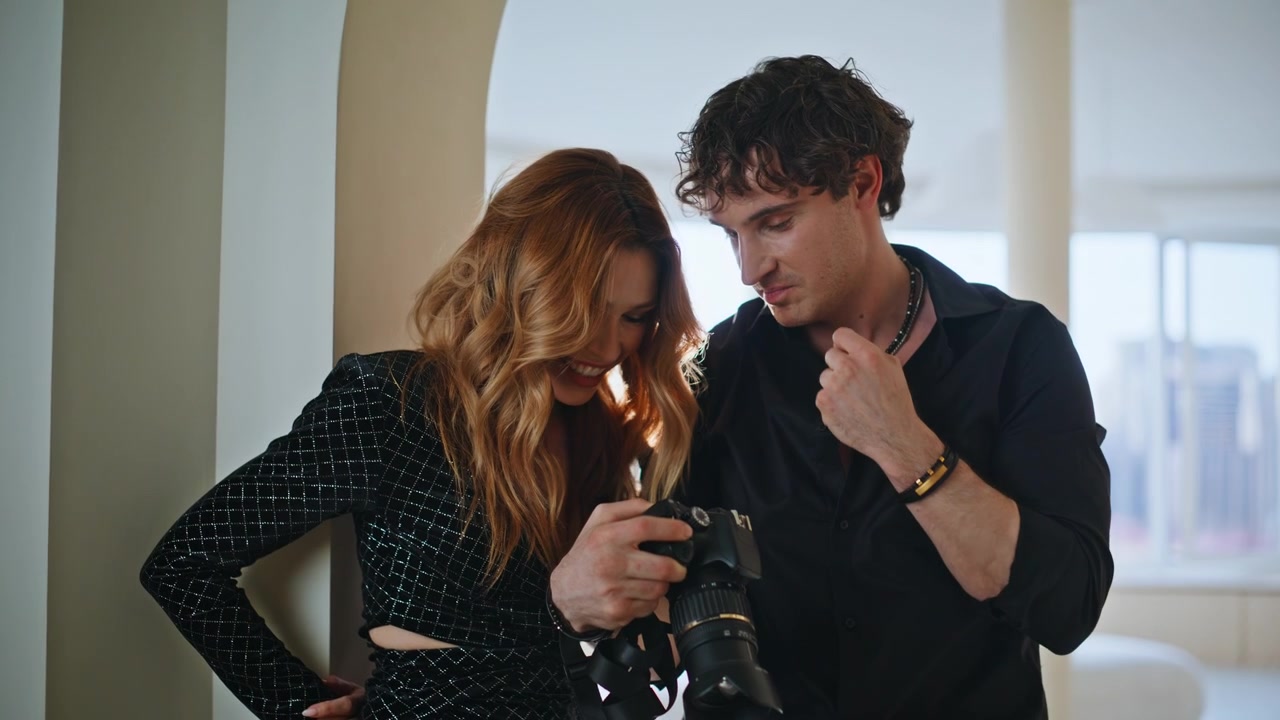 Fotógrafo e modelo visualizando fotos da câmera juntos. Casal alegre rindo na sessão de fotos