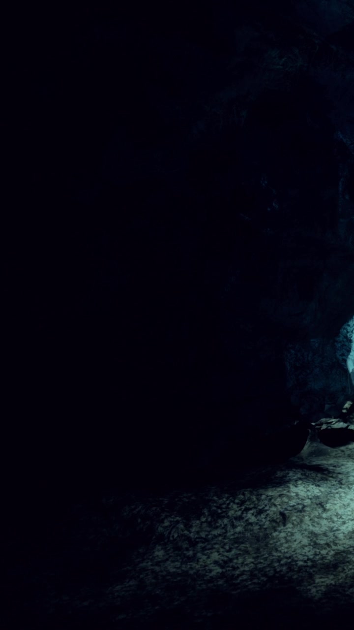 Exploring a dark cave with light illuminating rocky surfaces at night