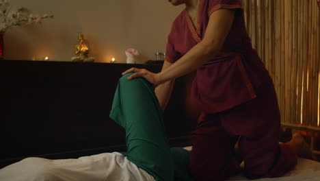 mujer asiática realiza masaje tradicional tailandés a una hermosa mujer europea. rehabilitación y tratamiento después de lesiones con la ayuda de masaje. relajarse y descansar de masaje de piernas brazos y espalda. masaje terapéutico