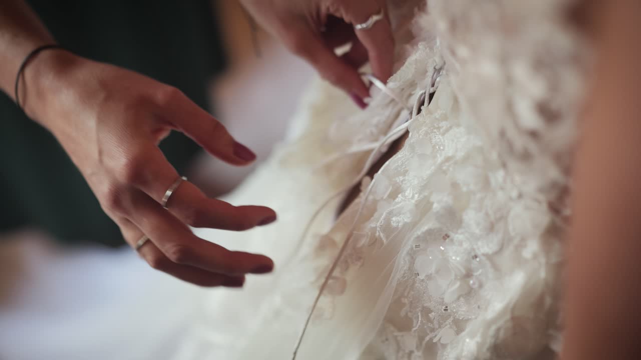 Close-up of someone adjusting a detailed wedding dress with care