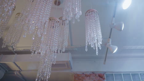 beautiful crystal chandeliers with cascading beads hang from ceiling in softly lit room. light reflects through hanging crystals, creating delicate sparkle and upscale ambiance