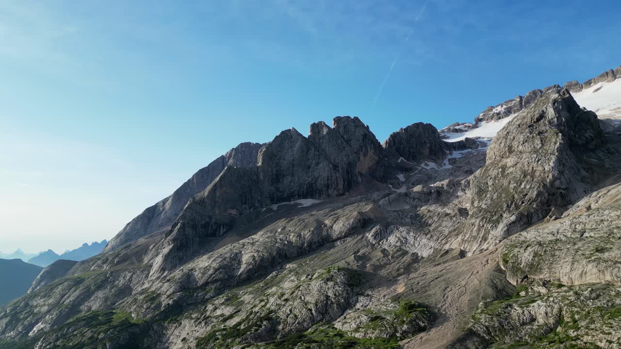 Dolomite peaks under clear blue skies, with patches of snow on rocky slopes