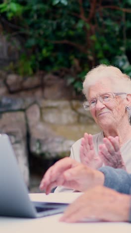 senior woman applauding in front of a laptop