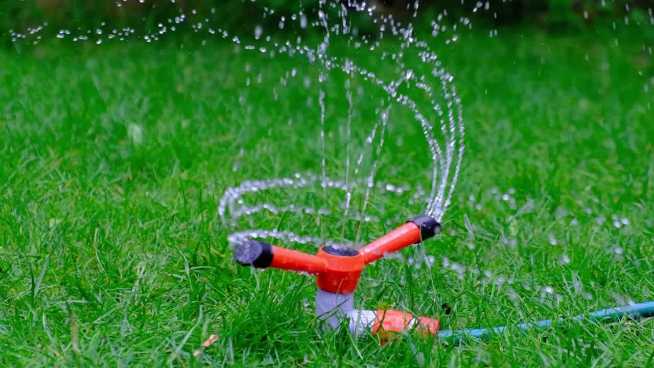 garden sprinkler rotating in circles and gushing water onto the grass. close up in slowmotion