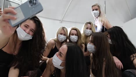 glamorous girls in masks taking selfies on a smartphone, posing in sexy clothes for a photo. coronavirus concept