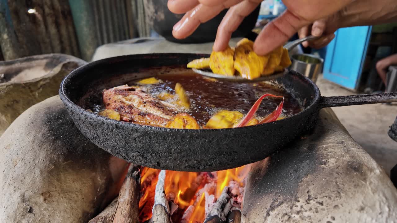 Dominican traditional food serving fried fish with fried plantains from a firewood stove