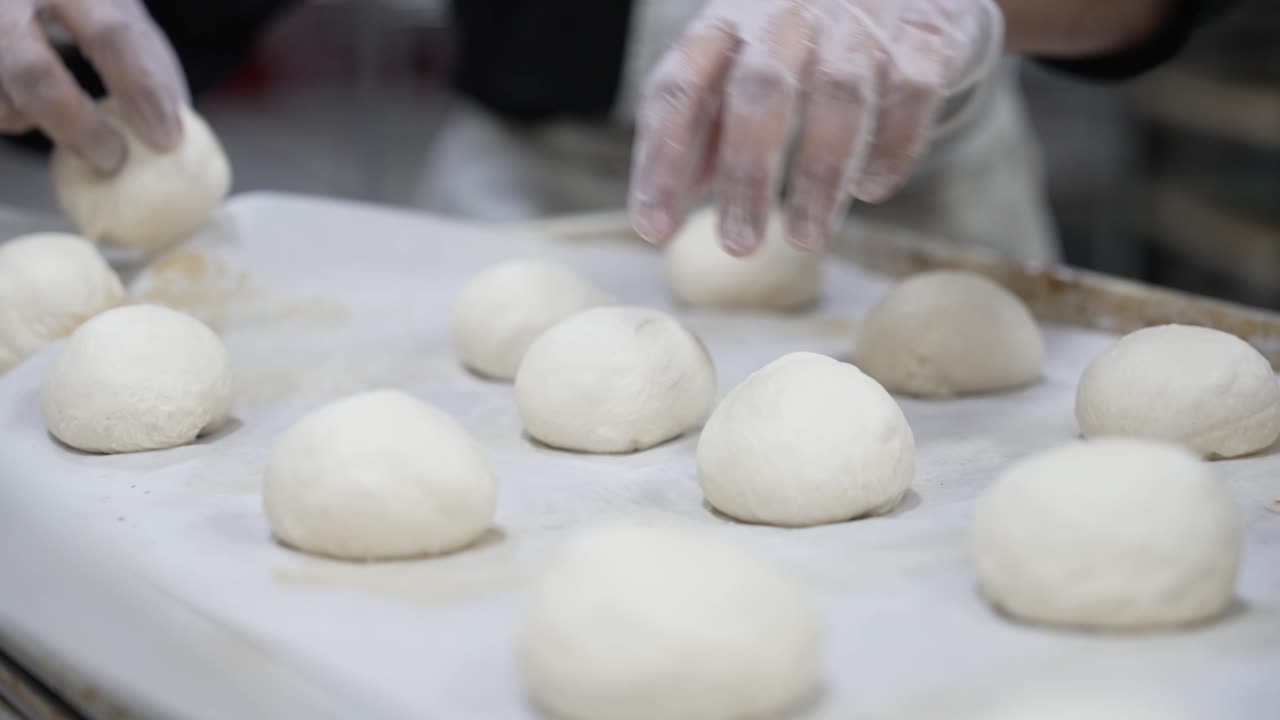 Baker preparing round buns for baking
