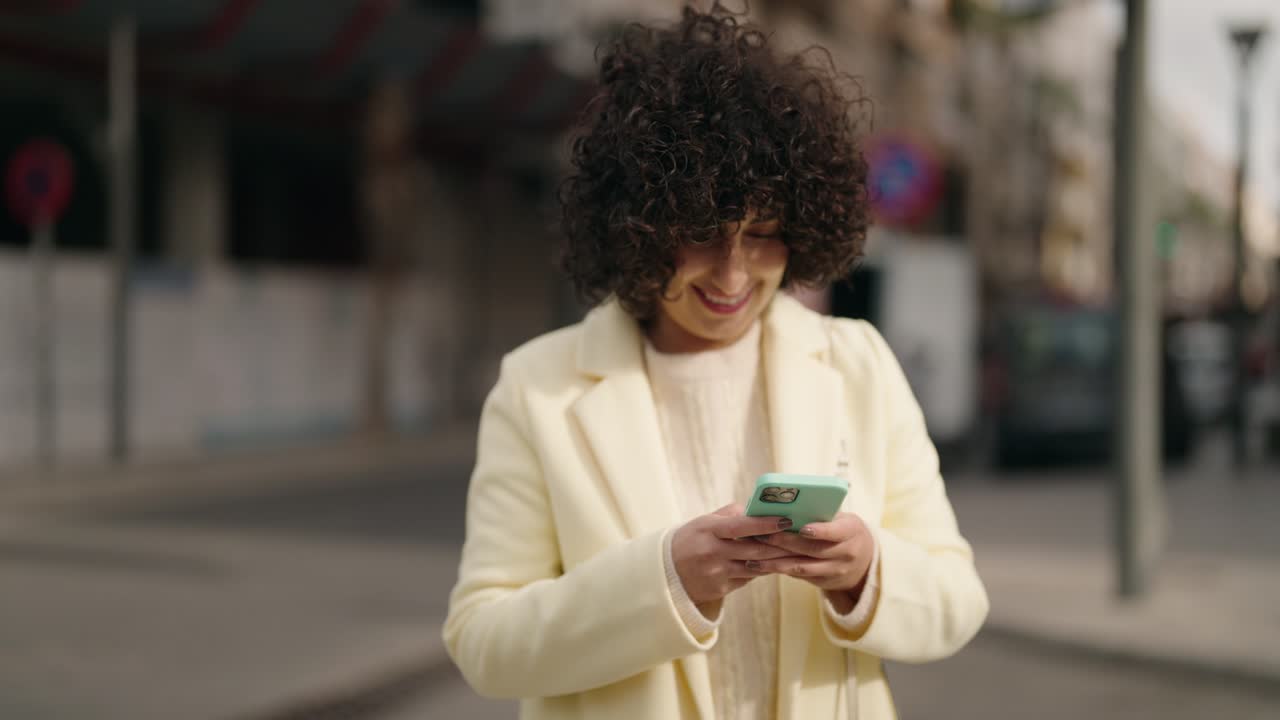 Young woman smiling confident using smartphone at street