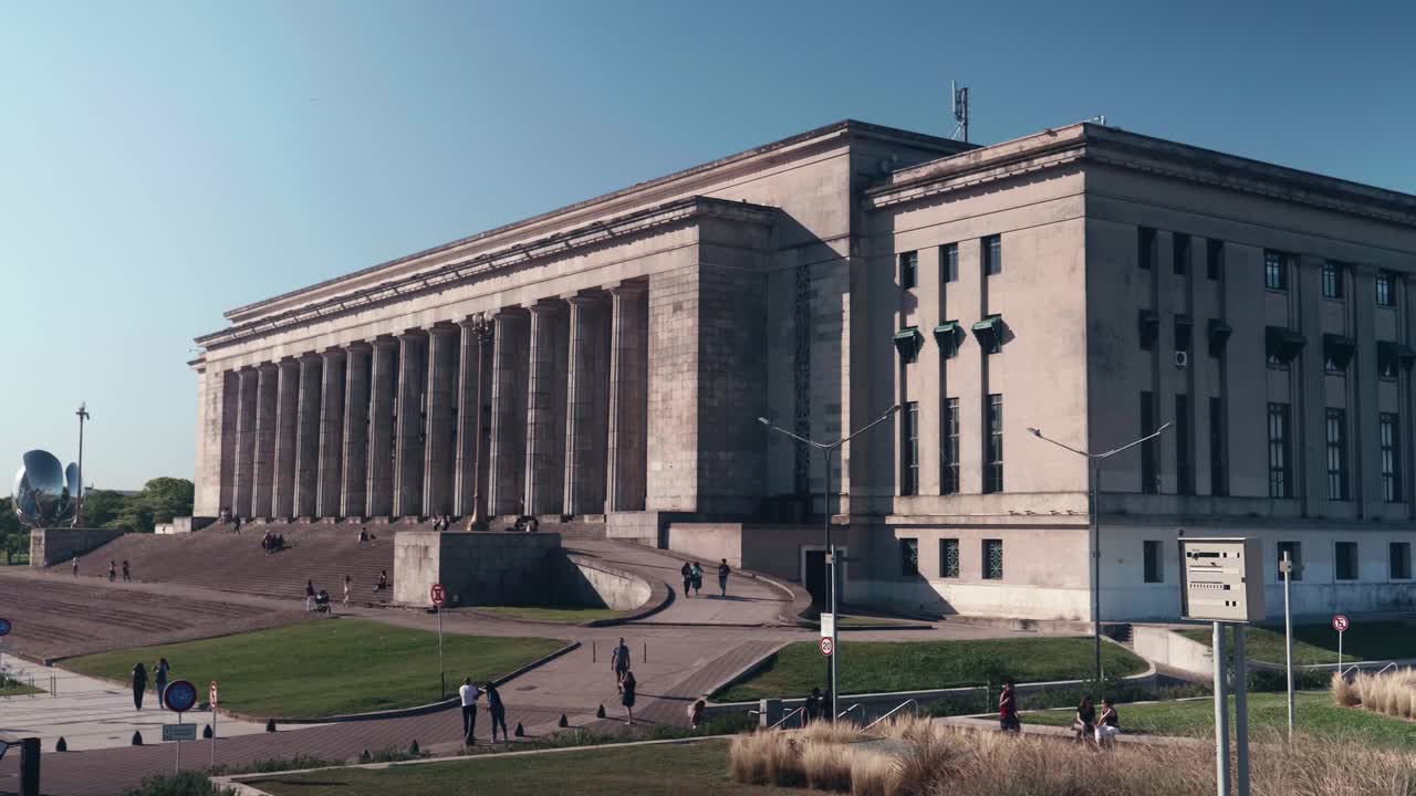 Persone che camminano intorno a un grande edificio classico in una giornata di sole