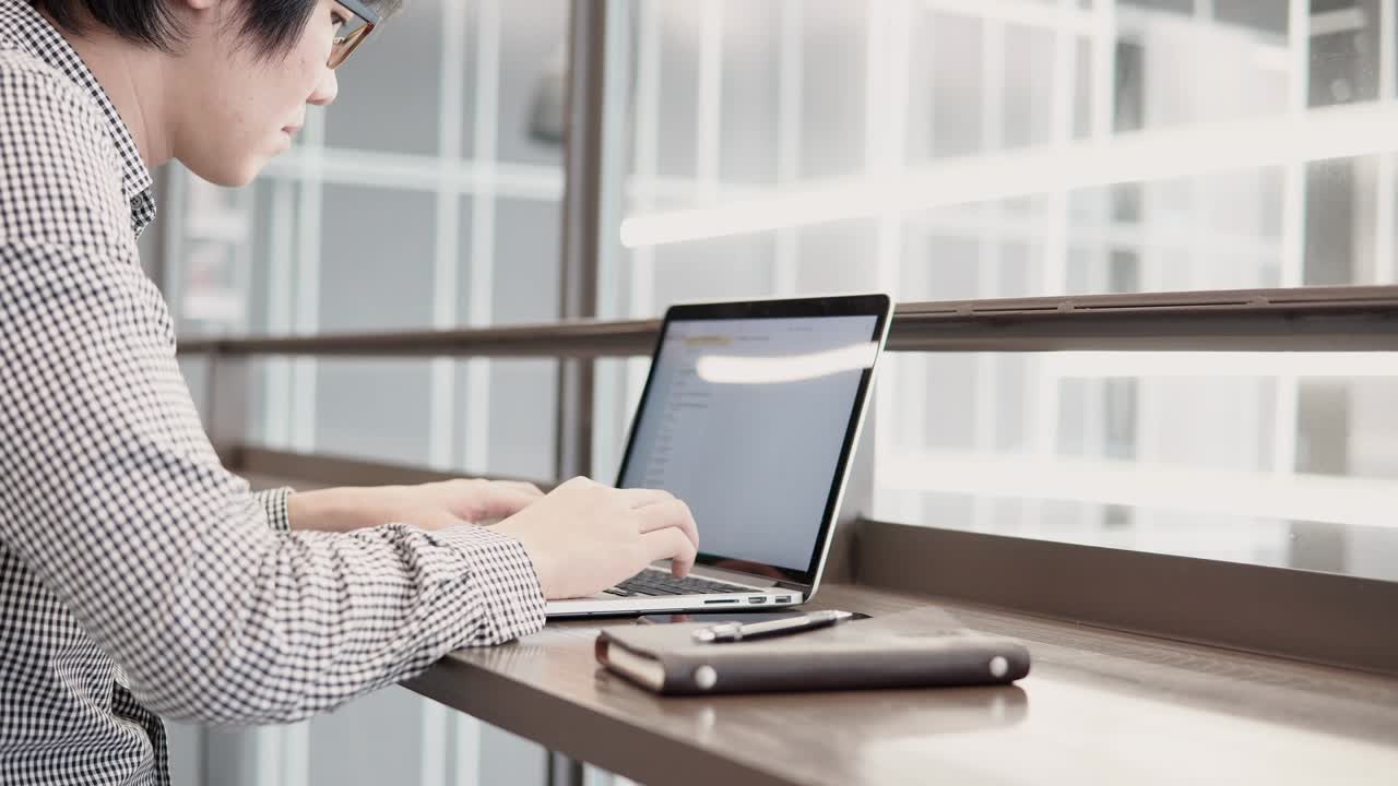 젊은 아시아 사업가, 작업 공간에서 노트북 컴퓨터를 사용하고, 나무 책상 위에 스마트폰과 노트북을 가지고, 노트북 키보드에서 남자 손으로 타이핑하고, 디지털 시대의 프리랜서 라이프 스타일.