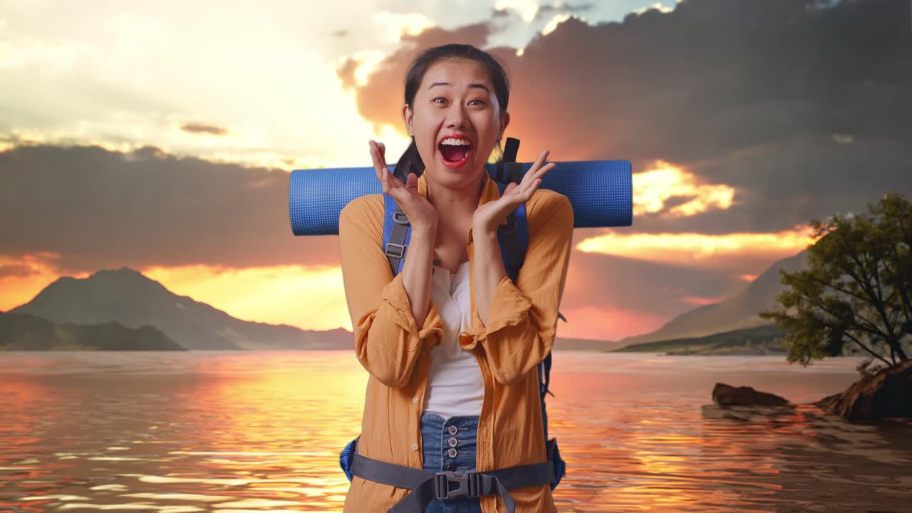 Asian Female Hiker With Mountaineering Backpack Saying Wow While Standing At A Lake During Sunset Time