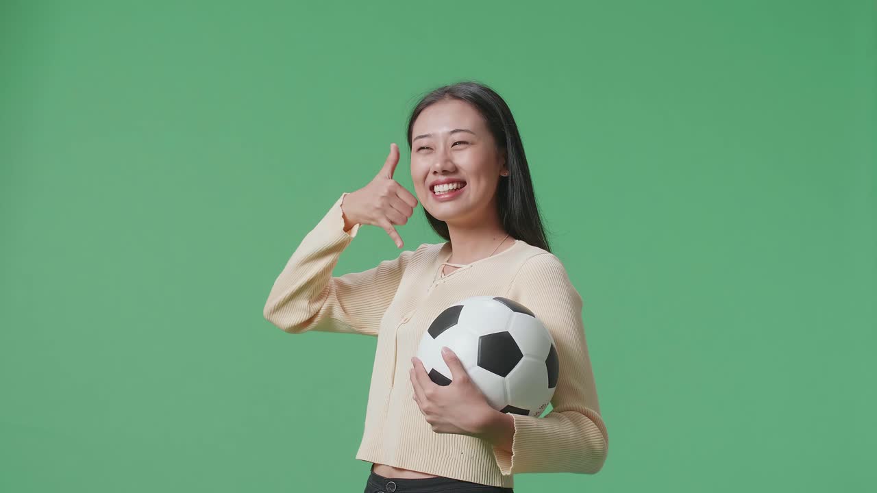 축구공을 들고 전화 제스처를 하는 여자