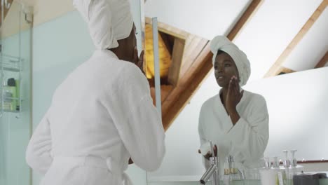 Retrato-De-Una-Mujer-Atractiva-Afroamericana-Aplicando-Crema-Facial-En-El-Baño