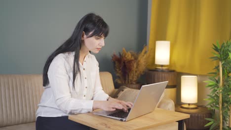 woman focusing on computer has serious expression. at home at night.