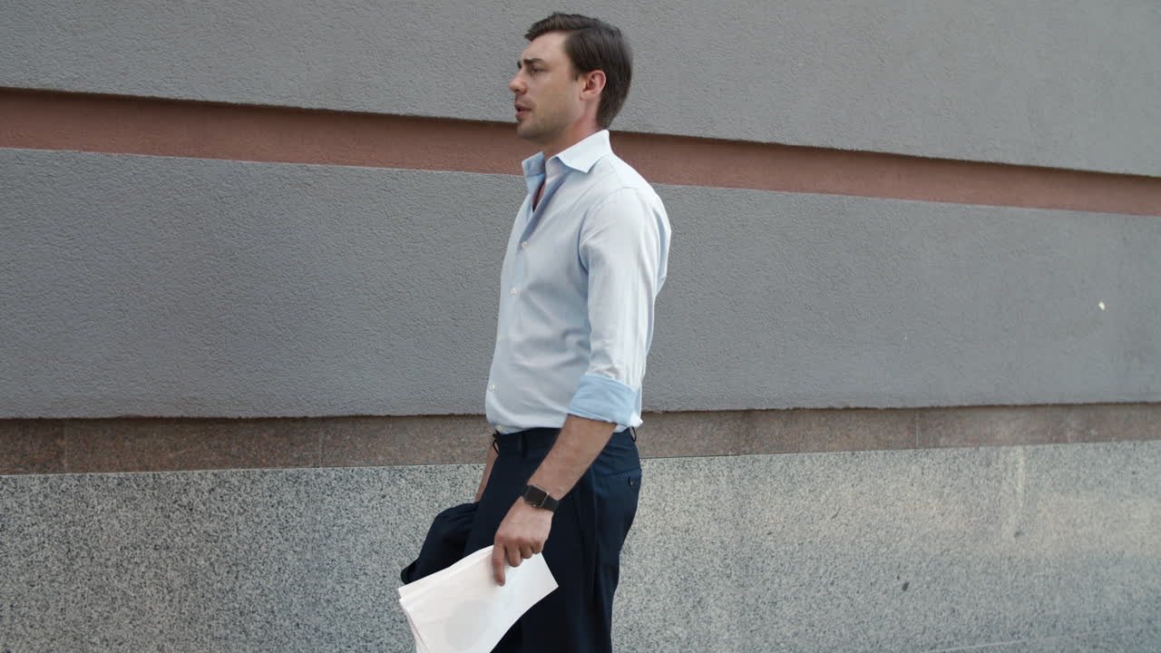 Primo piano di un uomo d'affari che cammina con documenti per strada. Uomo che tiene in mano dei documenti all'aperto.