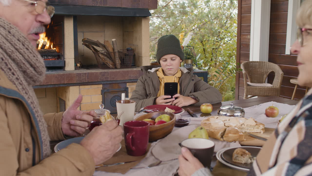 Family enjoying outdoor meal with fireplace in autumn