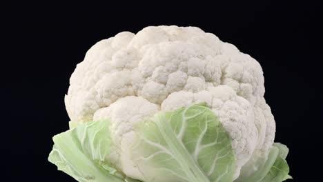 fresh raw cauliflower rotating over black background