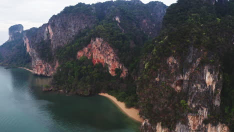 Small-sandy-beach-hidden-between-high-rock-cliffs-on-coast-of-Thailand