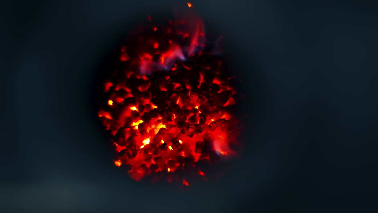 A heap of charcoal burning red in the furnace at large silo complex. Red, yellow and blue flashes of fire close up.