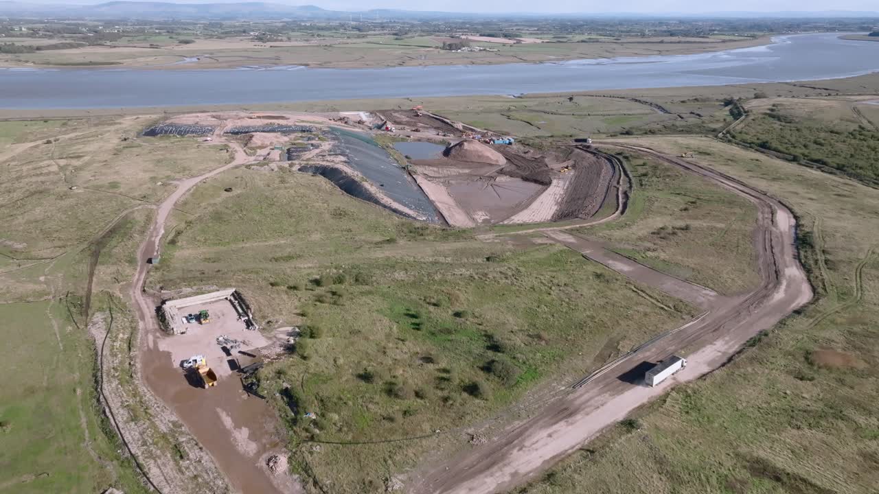 Large Landfill Hill With Working Vehicles Moving Trash Next To River Wyre. Jameson Road Landfill And Recycling Site, Fleetwood, UK