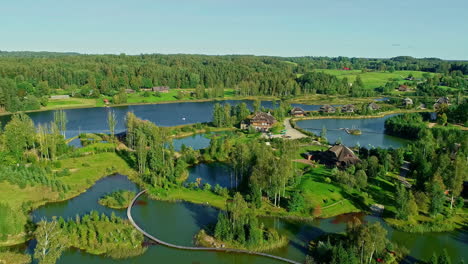 pull-back revealing drone shot of lush green wilderness village with lakes and ponds all around