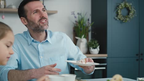 Unerkennbare-Frau-Schneidet-Osterkuchen-An-Und-Reicht-Im-Hintergrund-Ein-Stück-An-Die-Familie.