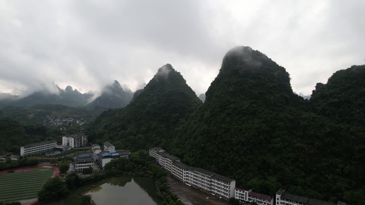 vuelo aéreo hacia atrás de la montañosa ciudad de yangshuo cubierta por nubes, china