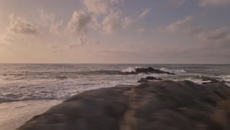 rocky dramatic splashing waves on sunset coastal beach skyline dolly flying right