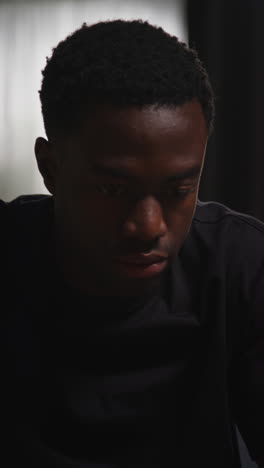 vertical video close up of unhappy and depressed young man sitting on sofa at home looking anxious and worried