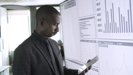 professional mixed-raced businessman standing near big screen