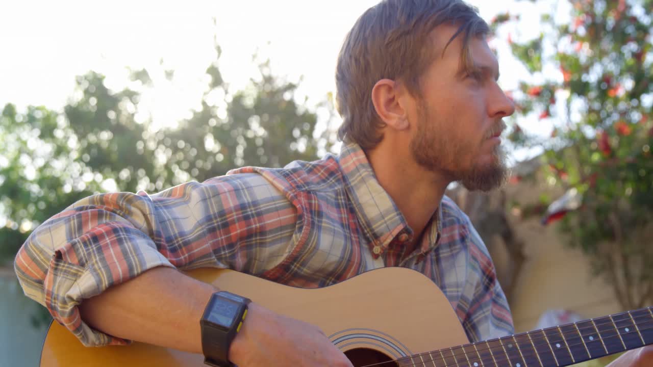 Homem tocando violão no jardim 4k