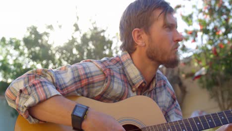 hombre tocando la guitarra en el jardín 4k
