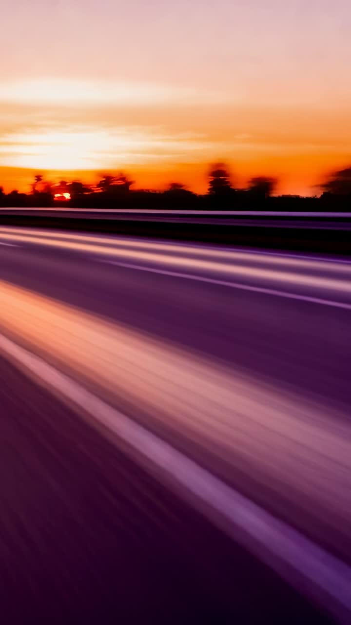 Video verticale: Il movimento dell'auto fa avanzare la telecamera lungo la strada al crepuscolo, trasmettendo velocità tramite striature.