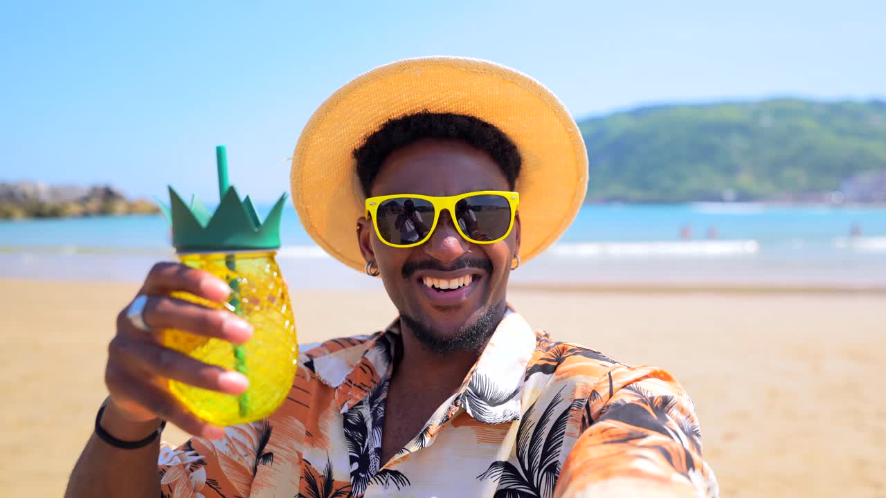 Uomo sulla spiaggia con occhiali da sole e cappello