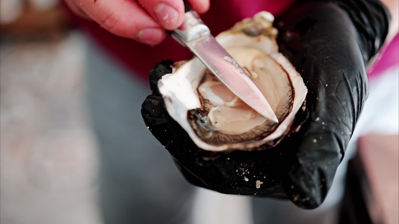 Close up of a waiter cutting a raw oyster at a restaurant