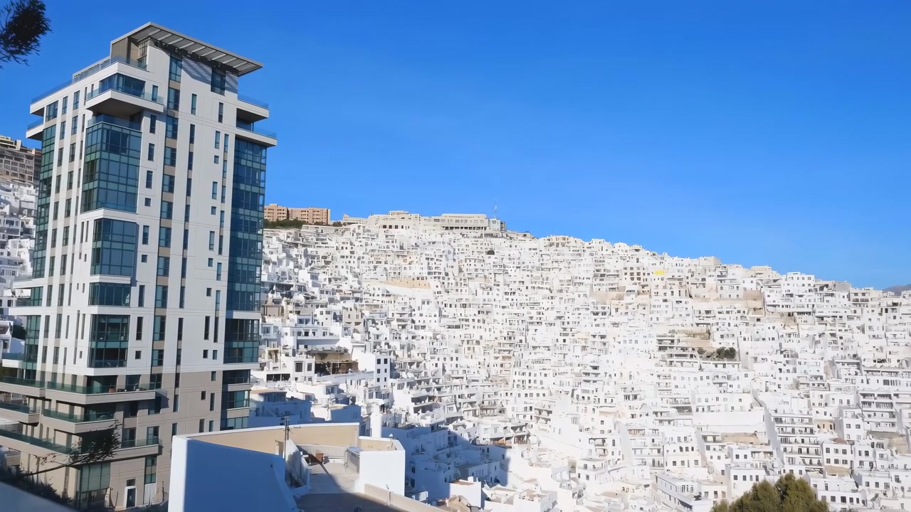 Un grattacielo immobile si erge in modo prominente in un paesaggio urbano, circondato da un grande cumulo di materiale bianco, forse detriti di costruzione o neve, durante la stagione invernale