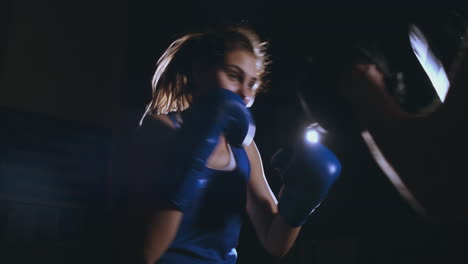 mujer adulta joven haciendo entrenamiento de kickboxing con su entrenador.