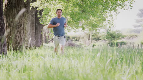 crane shot of man exercising running through countryside field