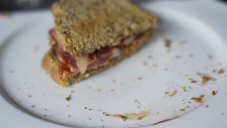 a yummy bacon sandwich being picked up from the plate to be eaten