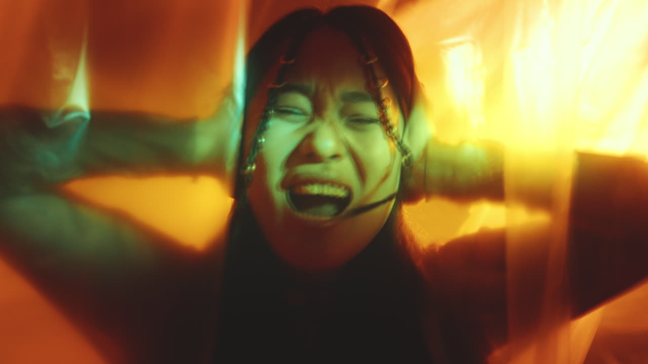 Emotionally Unstable Woman Covering Ears and Shouting in Dark Studio