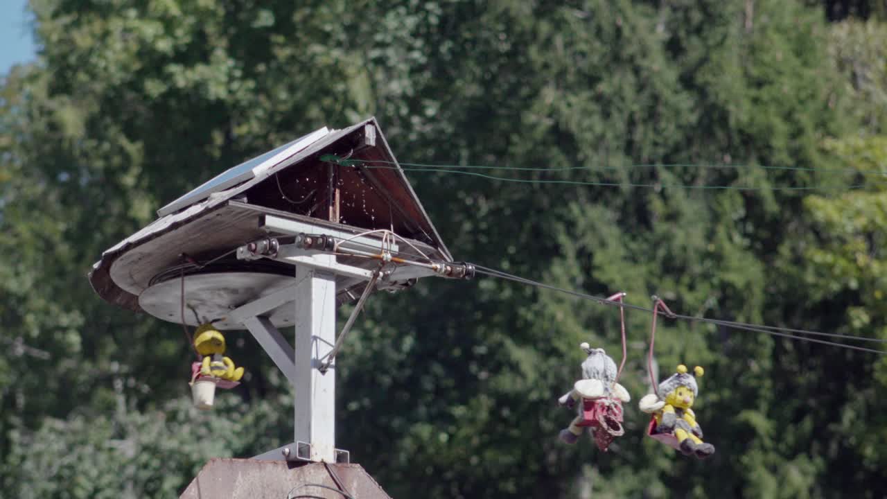 Hand held footage of a model chairlift with bee toys sitting on chairs in Folgaria, Alpe Cimbra, Trentino, Italy