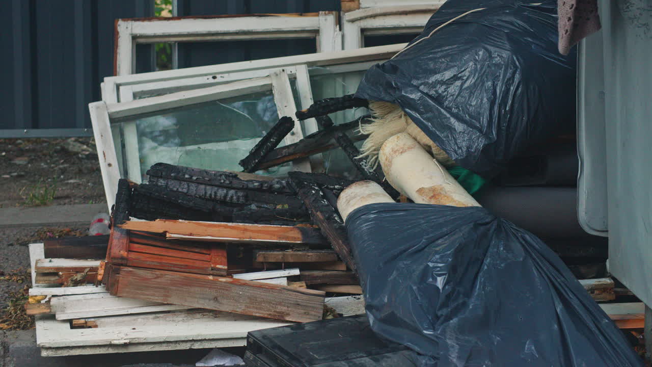 Abandoned construction materials, wood, furniture and burned frames and windows near a dumpster in Sofia, Bulgaria